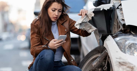 woman looking at phone after car accident